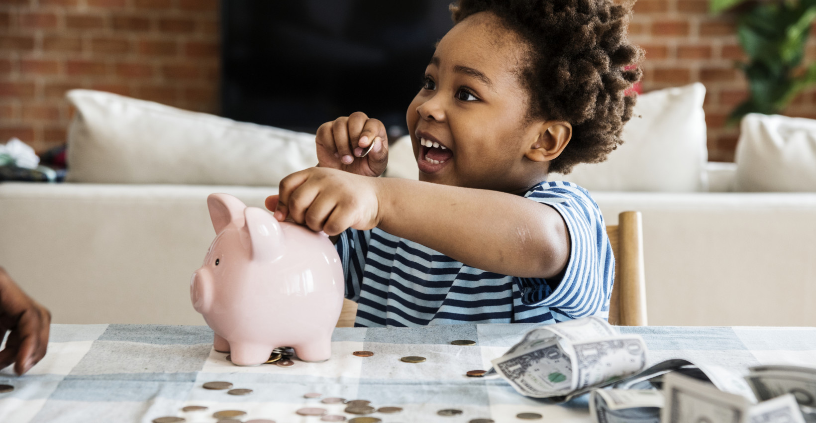 Young boy putting a coin in a piggy bank