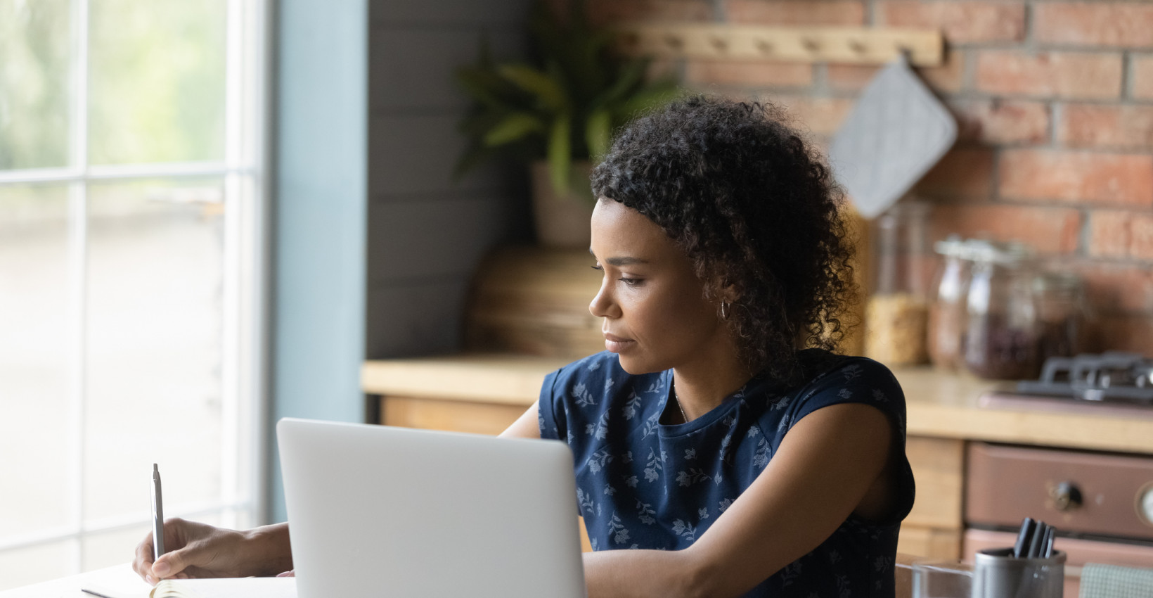 A woman working on her laptop at her kitchen table