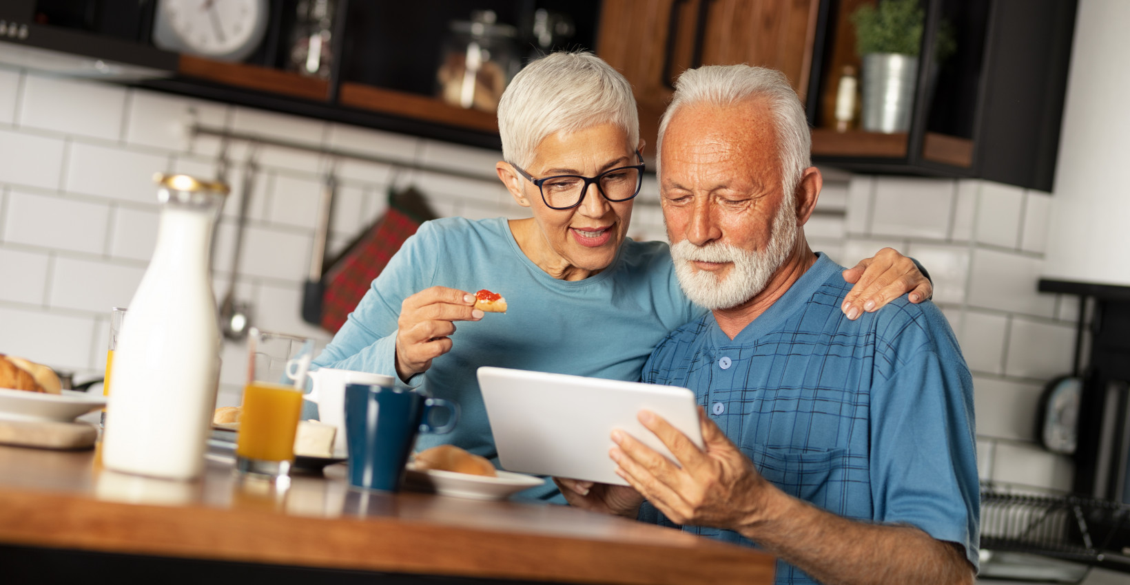 An elderly couple looking at a piece of mail at the kitchen table