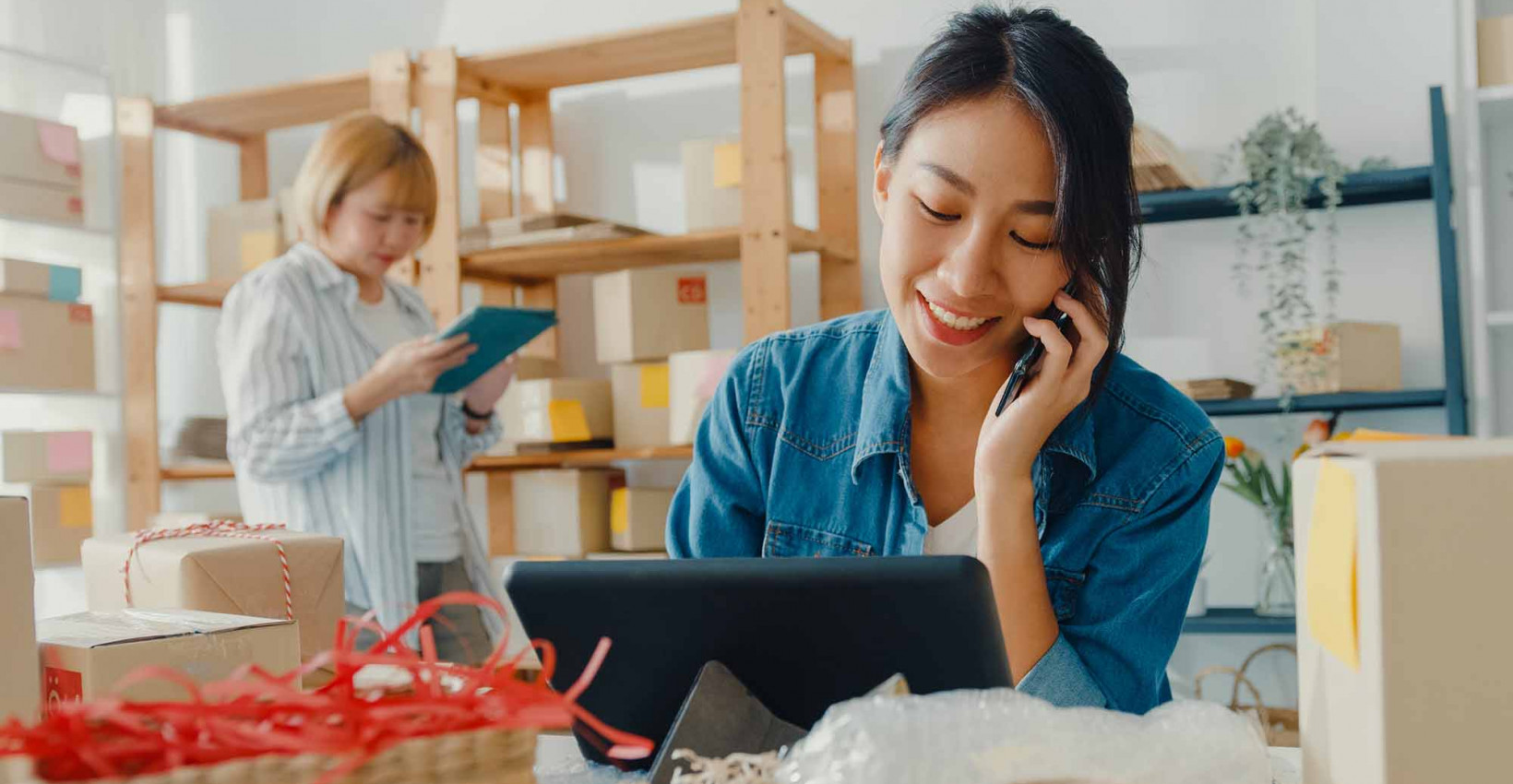 A woman working on a laptop and making a call on her cell phone