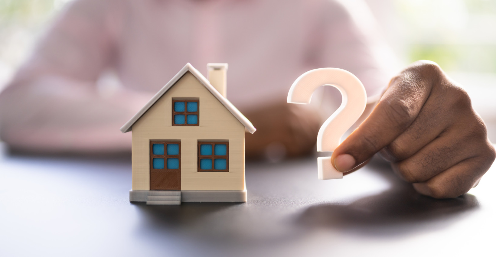 tiny house next to a man holding a question mark