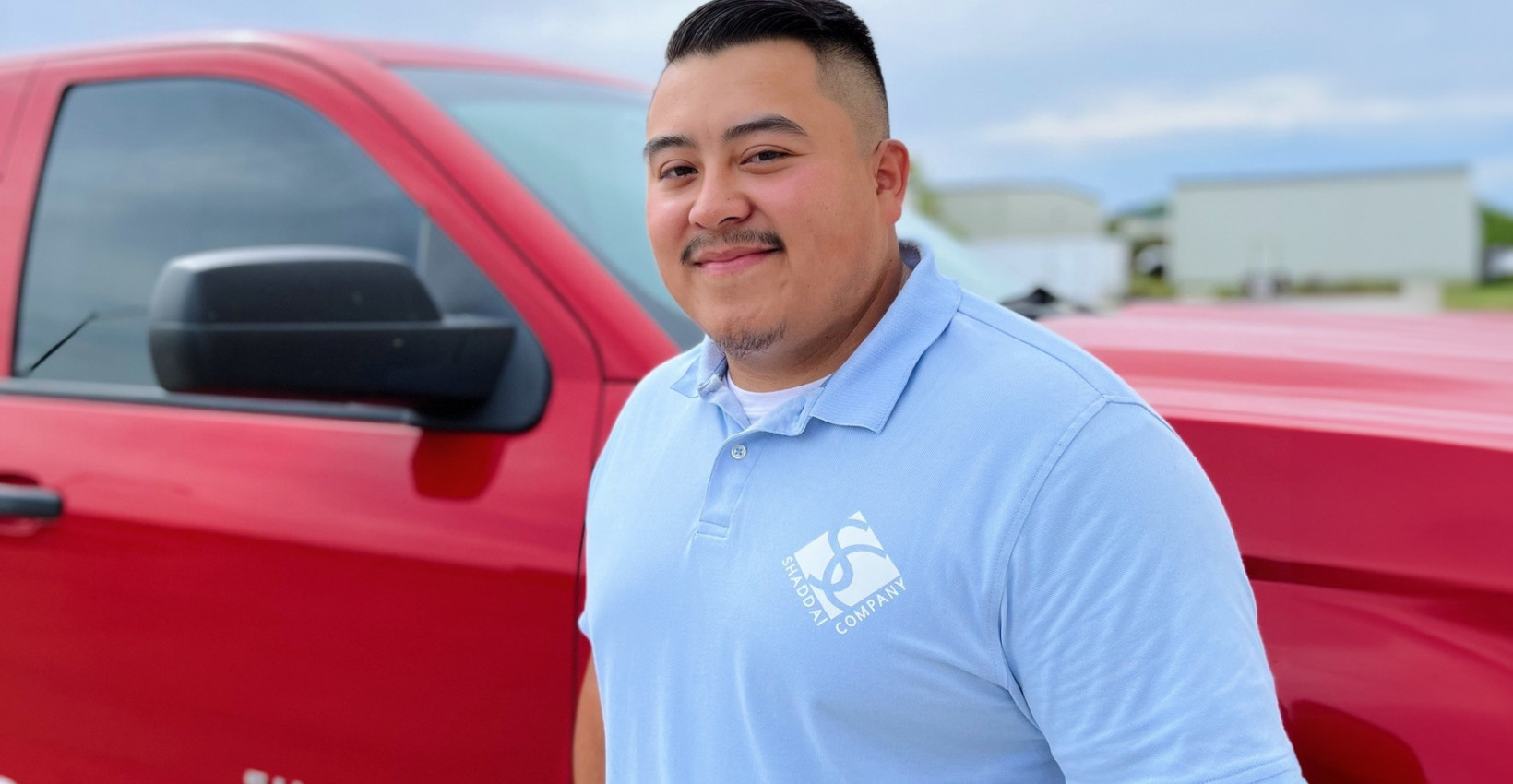 Luis Hong stands in front of his red truck