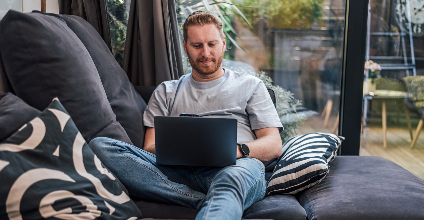 a man sits on a couch with his laptop