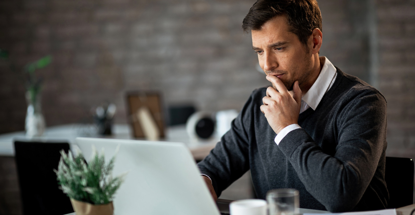 a guy looks at his computer thoughfully