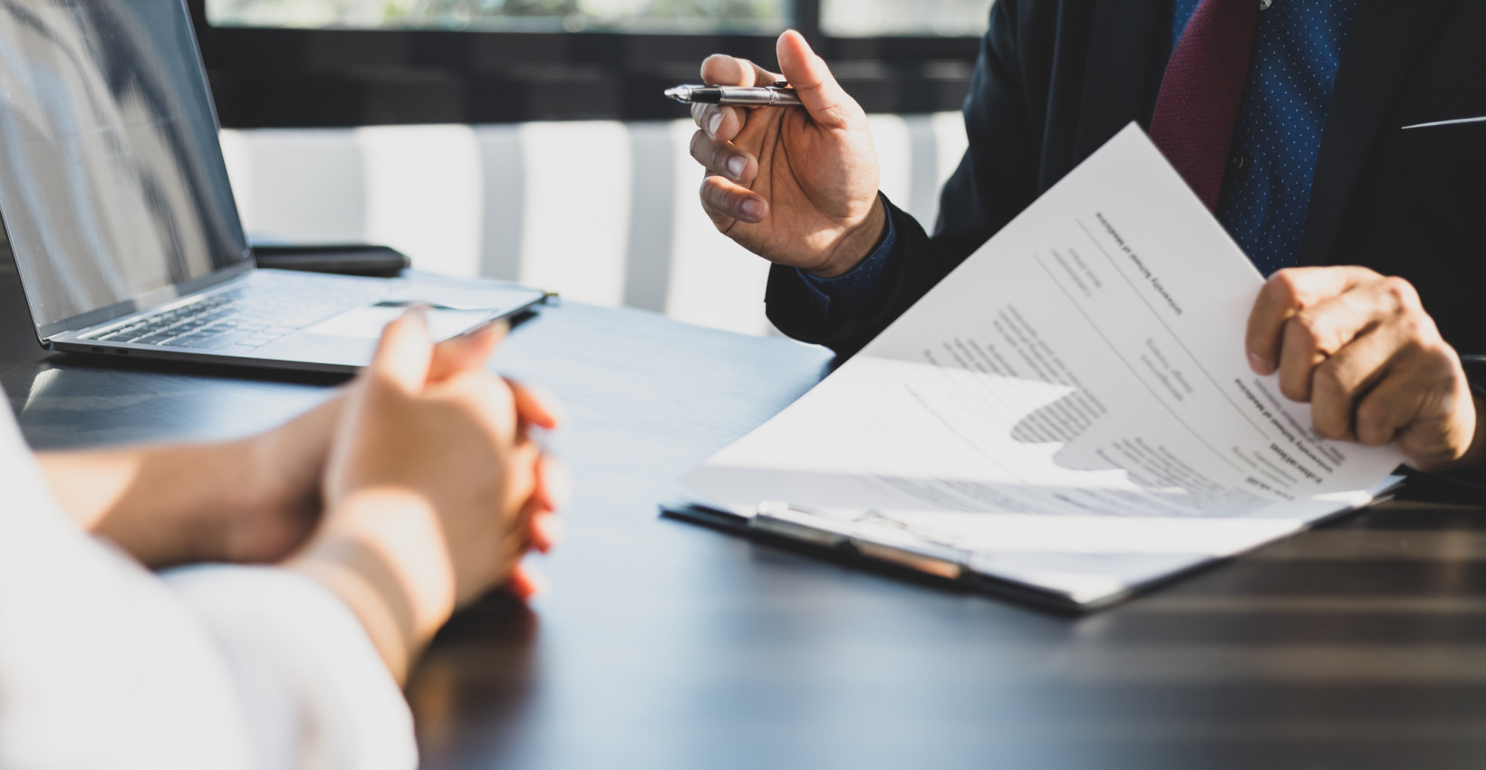 two people sit at a desk with paperwork
