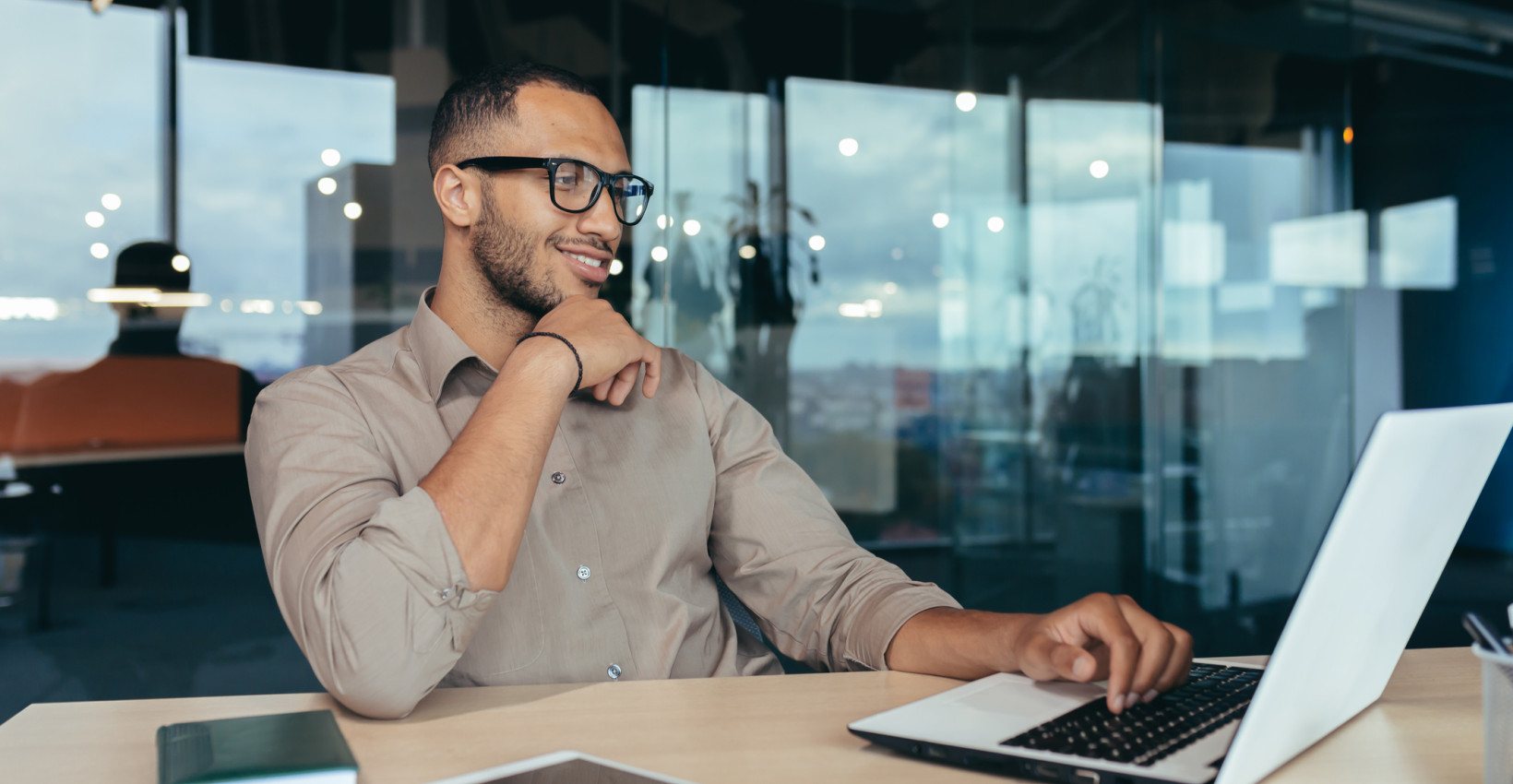 A man smiles as he looks at his laptop