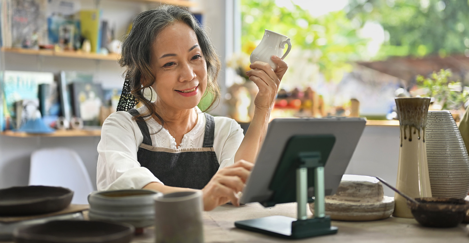 a woman with her phone in her hand looks at a tablet smiling