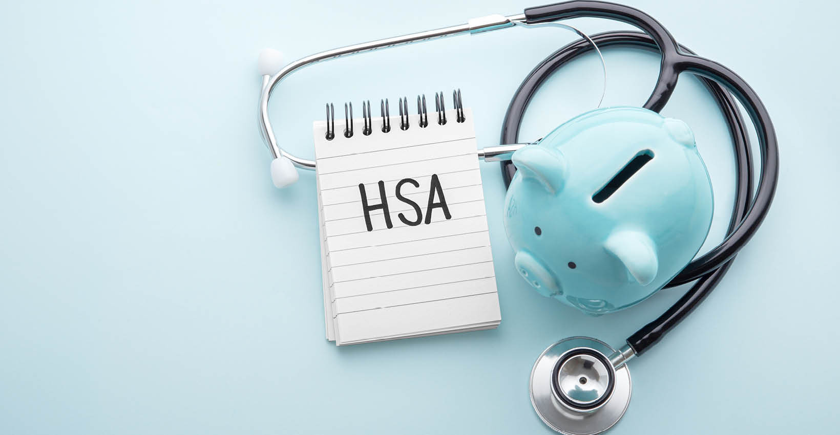 a blue piggy bank sits on a table with a stethoscope and notepad