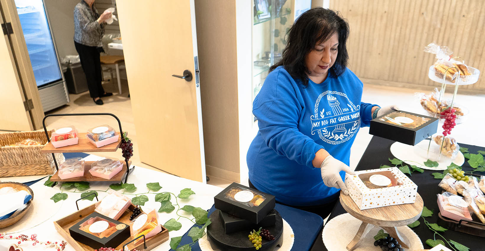 fay the owner of my big fat greek bakery stands at her table at union bank place pop-up shop