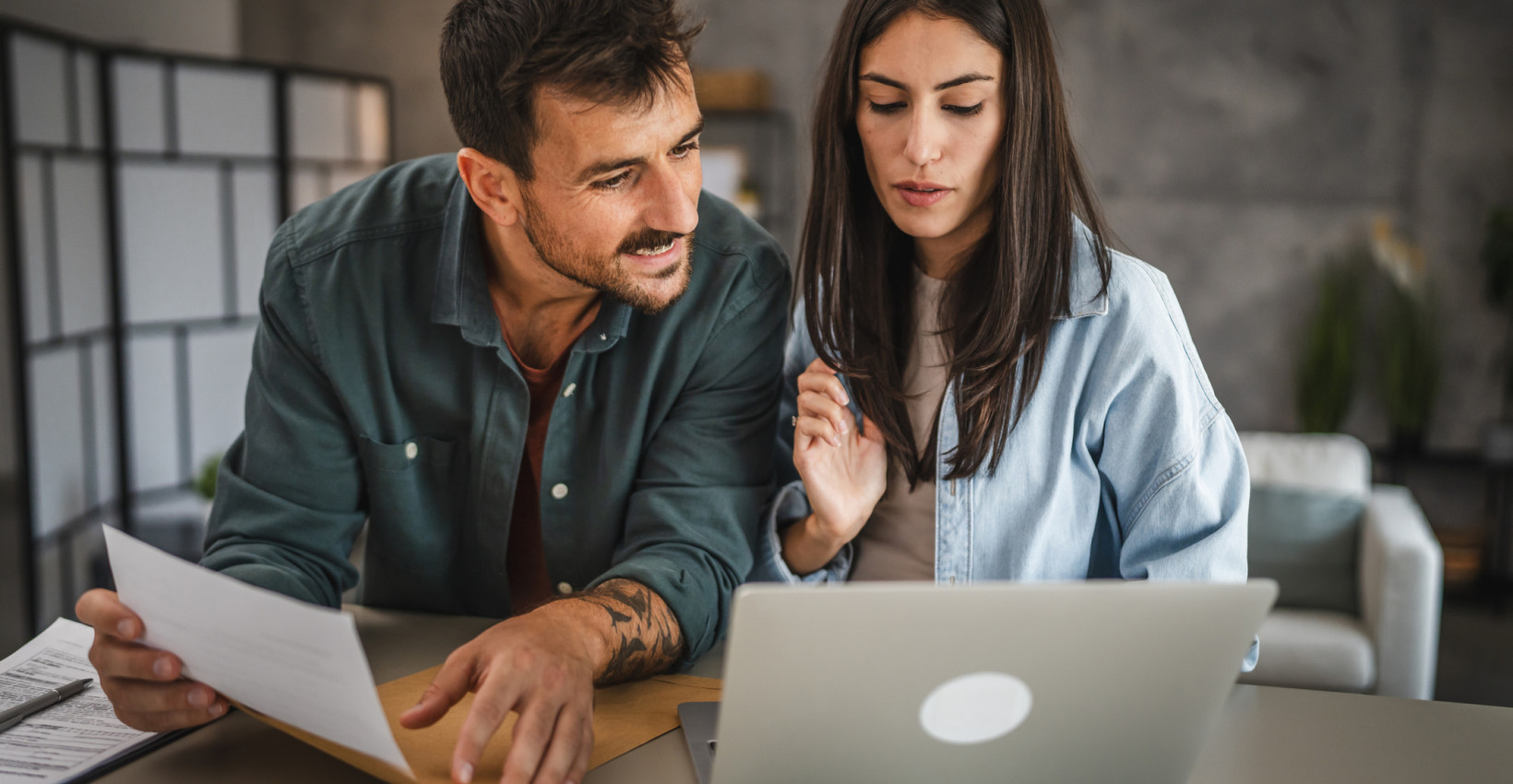 a man and a woman sit at a table with a laptop open