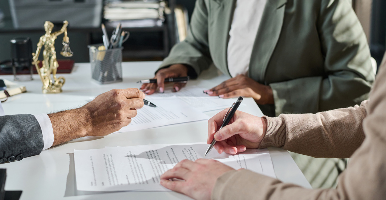 three people sit at a table looking at papers