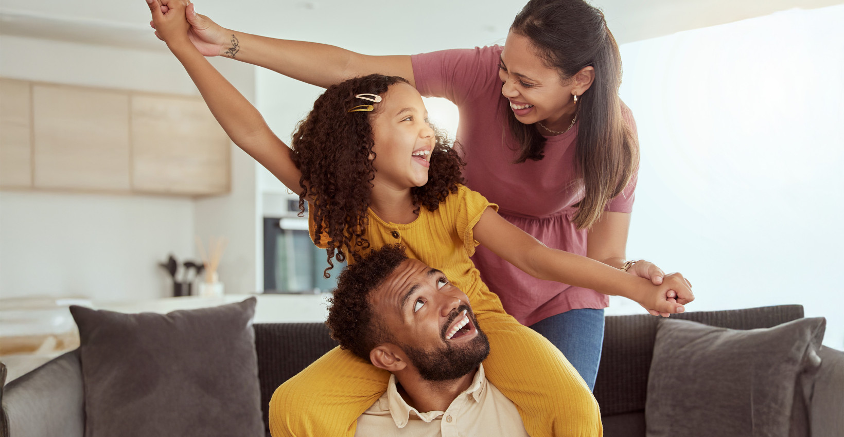 a mom, dad, and daughter play together laughing