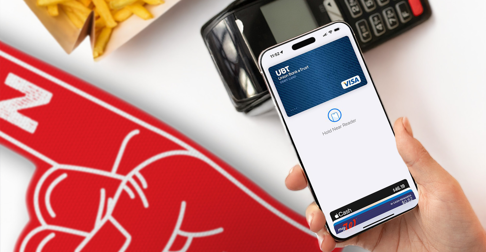 a hand holds a phone over a payment machine that lays next to a number 1 foam finger