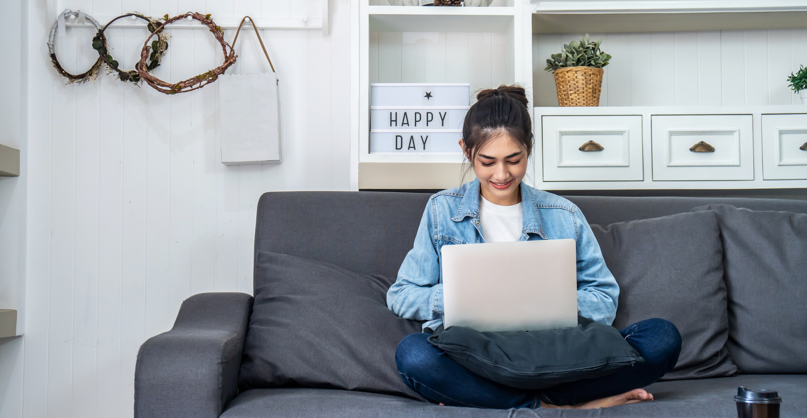a woman sits on a couch with a laptop on her lap