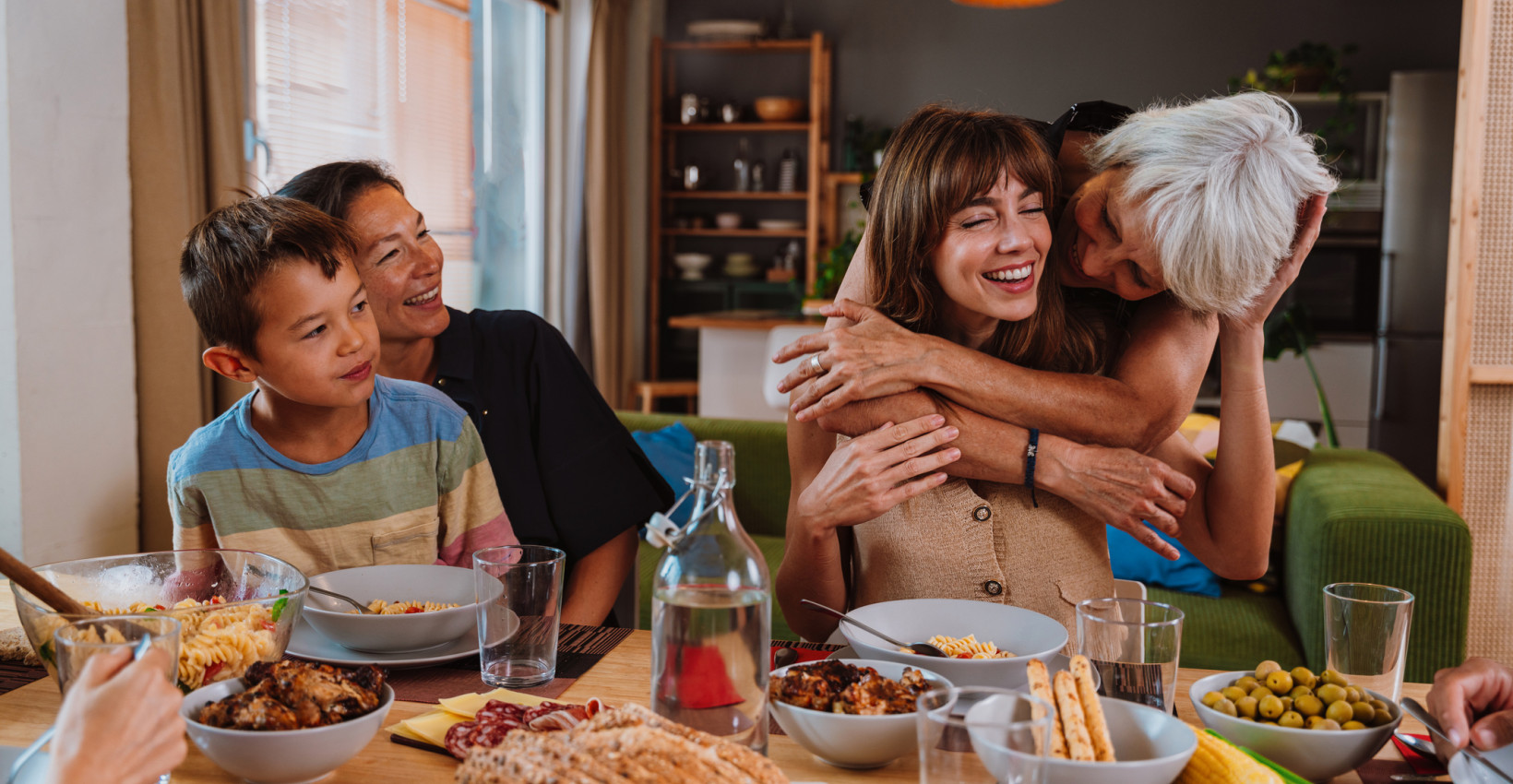 a family sits around a table laughing and hugging