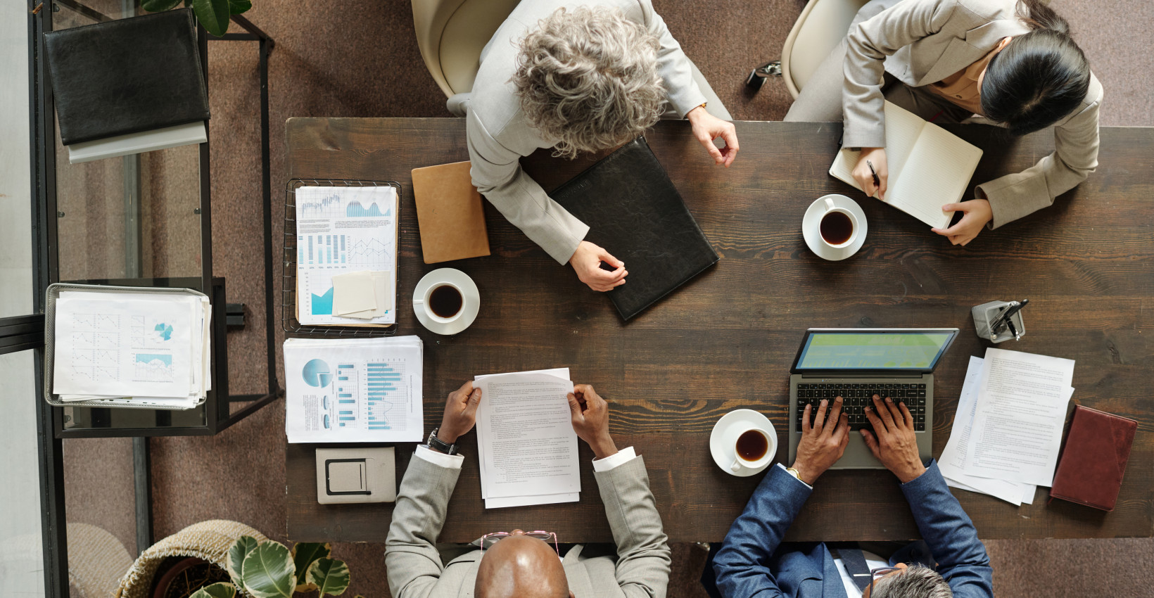 An overhead shot of 4 people having a meeting at a wooden table