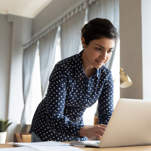 A woman standing and working on a laptop