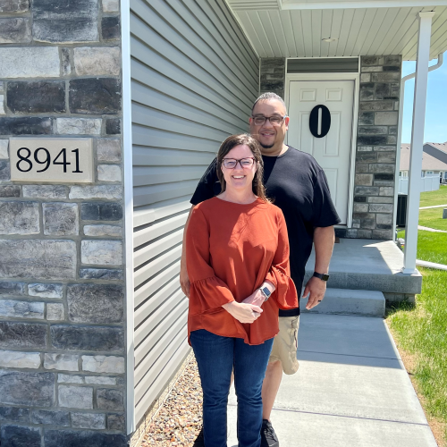 A couple standing outside of their new home. 