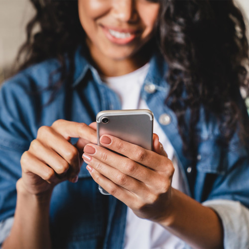 A woman smiling as she looks down at her phone