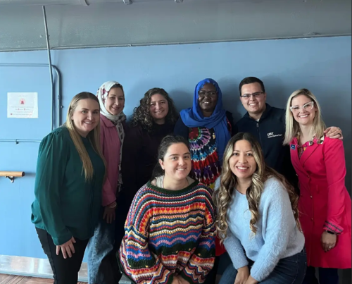 A diverse group of eight people smiling for a photo