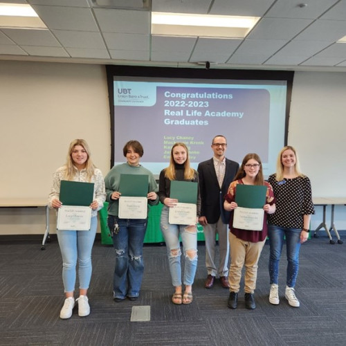 A few students holding up their certificates of completion for a program 