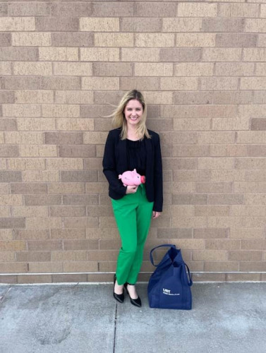 Brittany Planos against a brick wall holding a UBT piggy bank