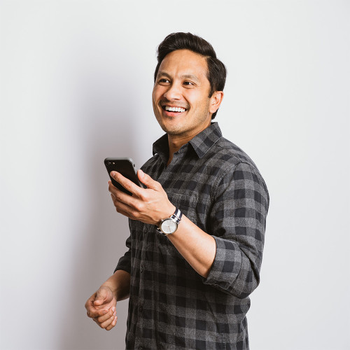 a man holds his cellphone while smiling