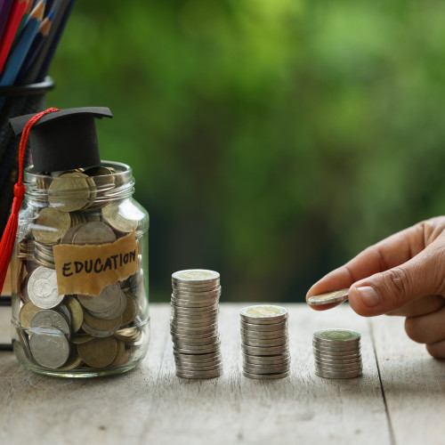 Someone stacking quarters next to a jar full of coins