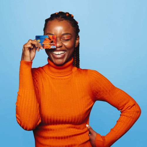 A woman holding a debit card up to her face and smiling
