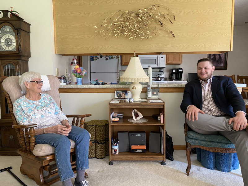 A young man and elderly woman sitting in arm chairs and smiling at each other