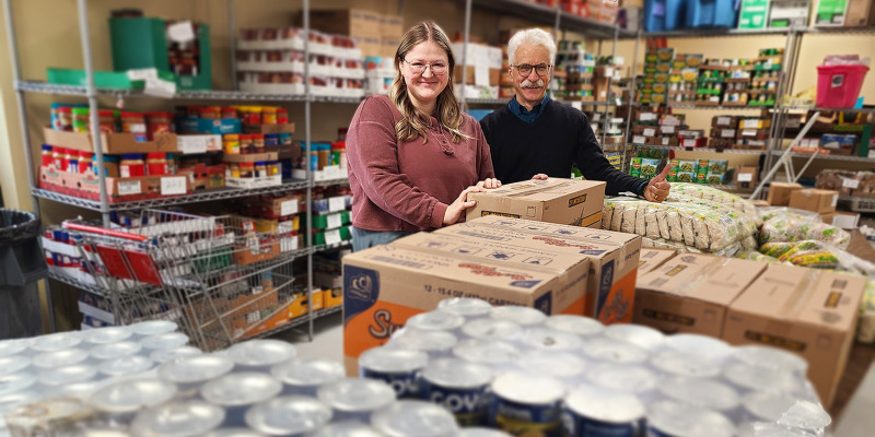 two people smile at the amount of canned food in front of them