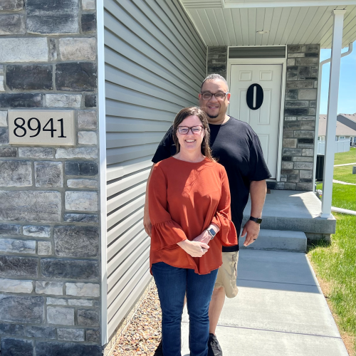 A happy couple standing outside their home