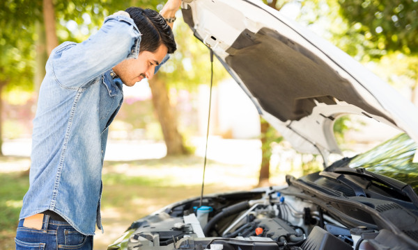 Person attempting to fix their car under the hood.