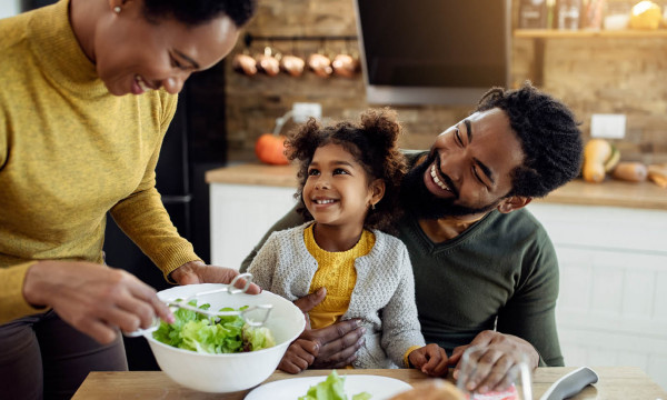 A mom serving salad to her husband and daughter