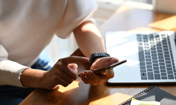 Person using a phone and a computer to enroll in e-statements
