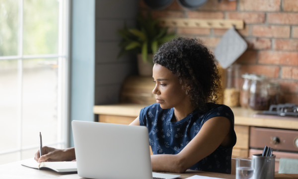 A woman working on her laptop at her kitchen table