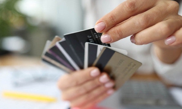 A woman holding a bunch of debit cards like a hand of playing cards. 