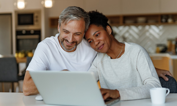 A husband and wife looking at a computer and cuddling for some reason. 