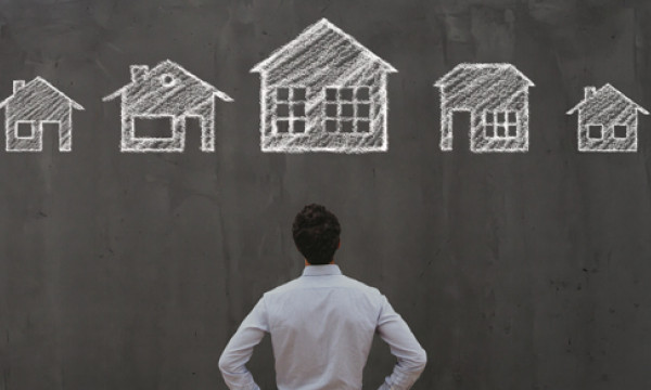 A man looking at a chalkboard with several houses drawn on it
