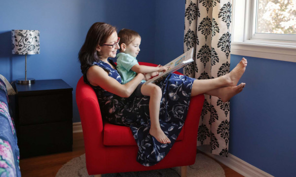 A mother and son reading a book by a window