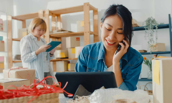 A woman working on a laptop and making a call on her cell phone