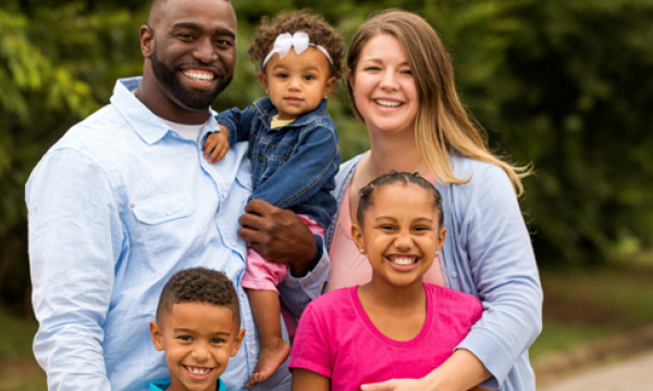 A husband, wife, and their three young kids posting for a family portrait