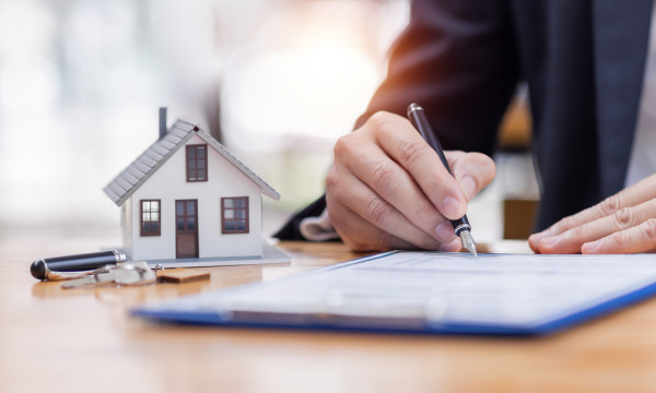 a person writes on a piece of paper next to a tiny house