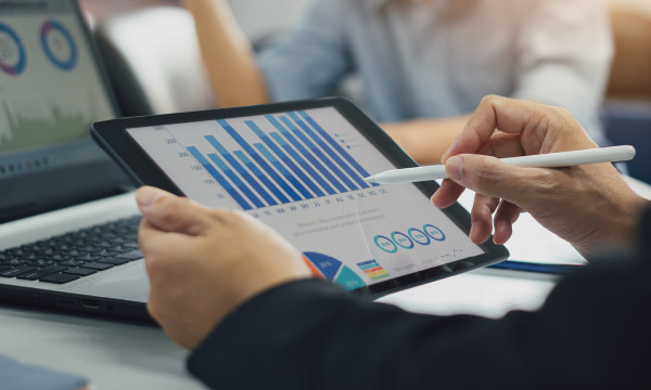 person holding a tablet looking at graphs