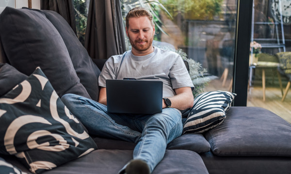 a man sits on a couch with his laptop