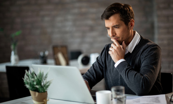 a guy looks at his computer thoughfully