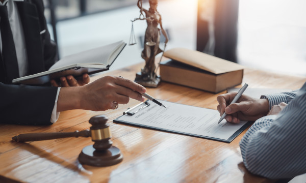 two people's hands on a desk looking at a paper