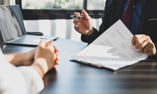 two people sit at a desk with paperwork