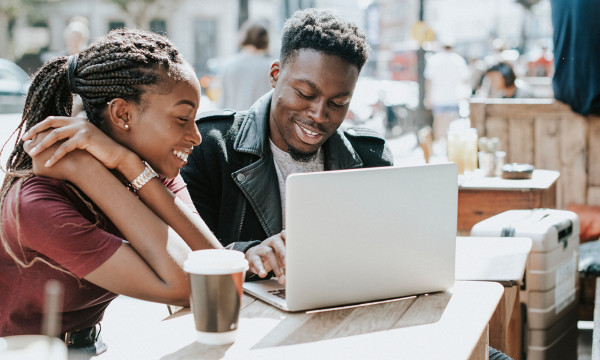 a couple sits at a laptop