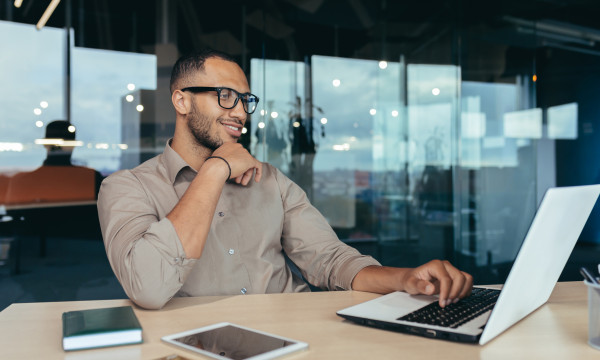 A man smiles as he looks at his laptop